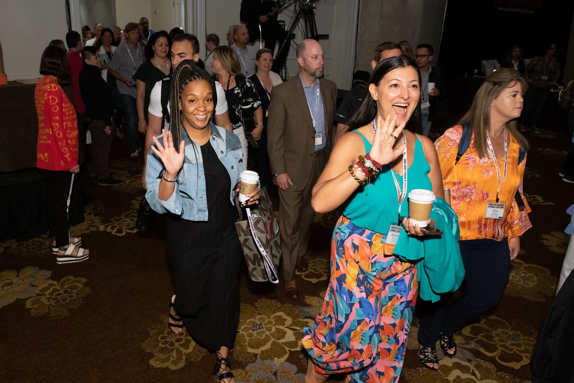 Law firm owners raising their hands in a large HTM conference room
