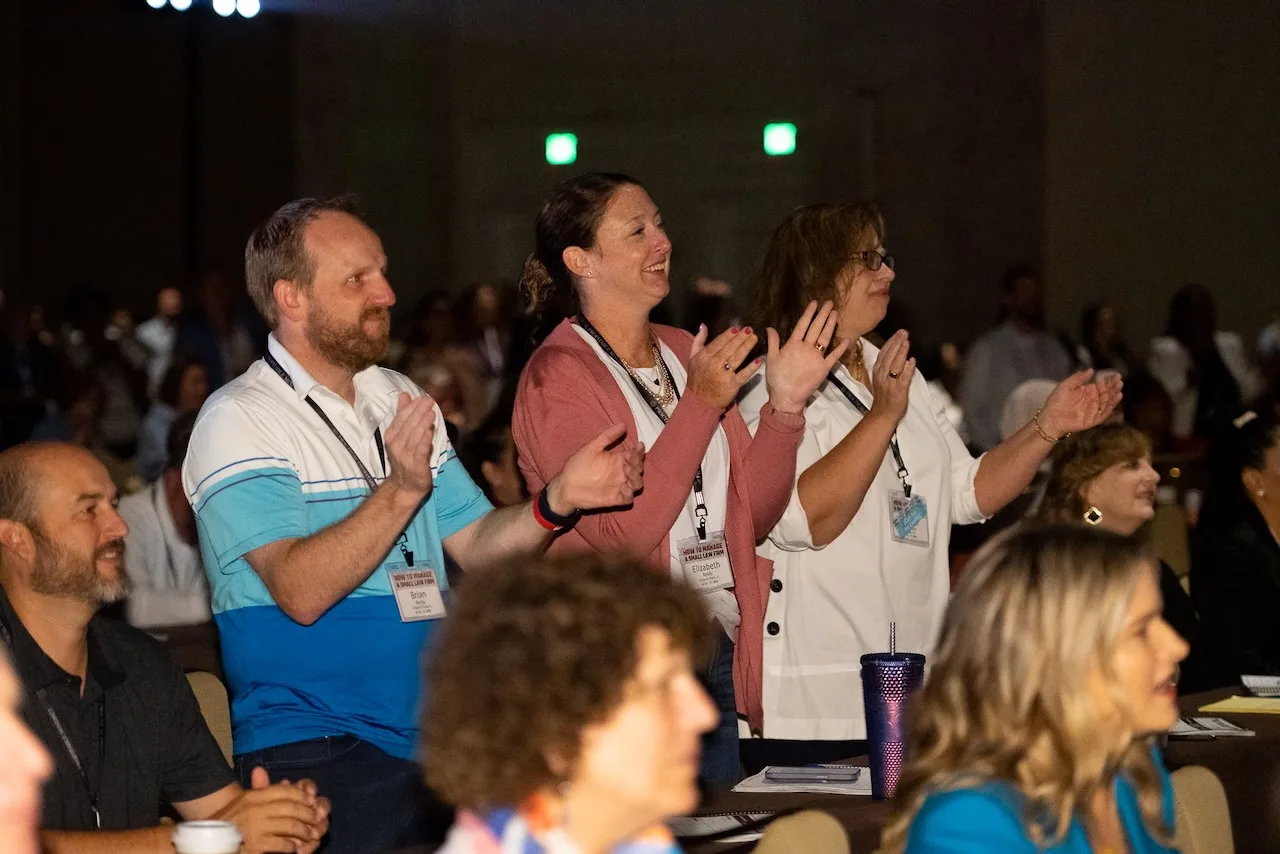 HTM members standing and applauding during a live event.