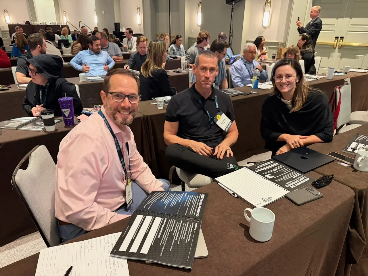 Three law firm owners smiling while working together at an HTM workshop.