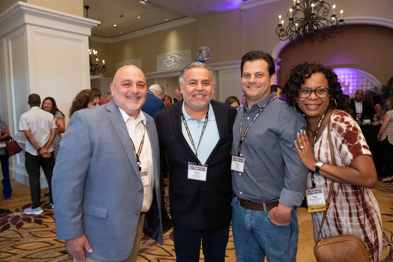 Four law firm owners smiling together during an HTM event.