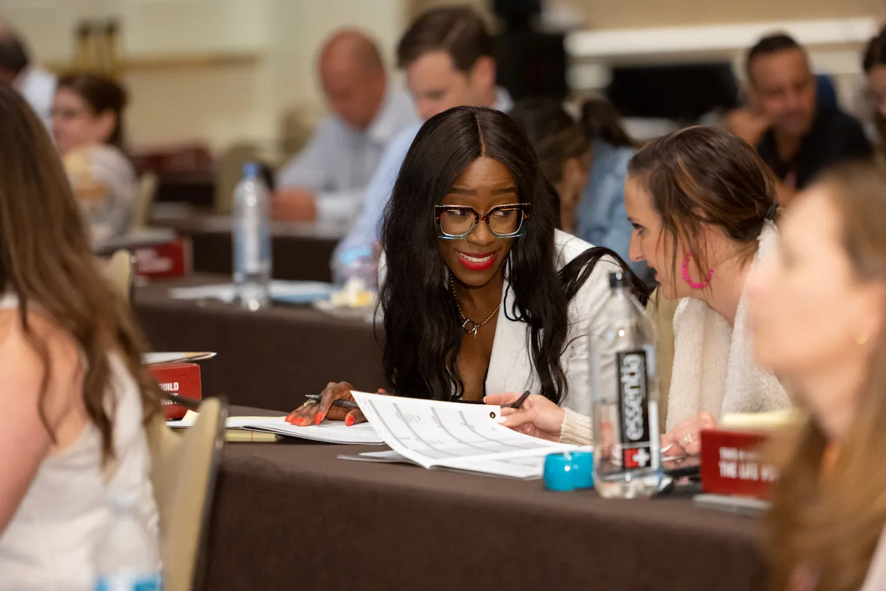 A law firm owner collaborating over workshop materials with a peer.