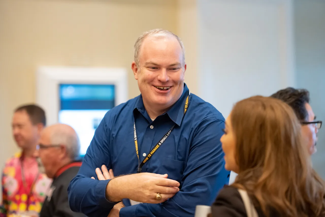 An HTM member smiling while speaking with fellow law firm owners.