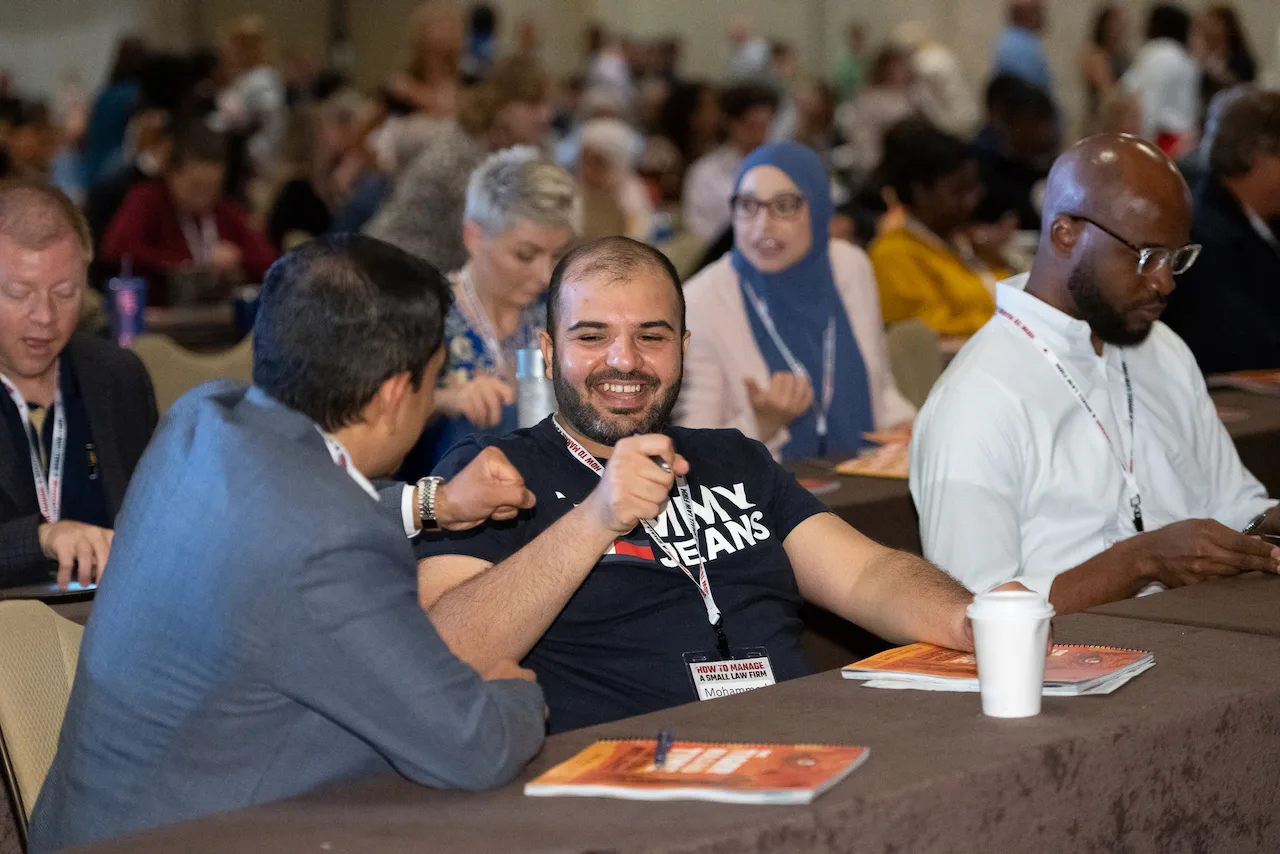 A smiling law firm owner connecting with peers during an HTM working session.